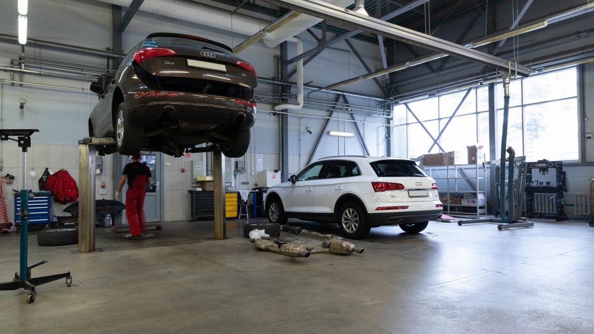 Officina con meccanici che riparano auto ibride e elettriche, con attrezzature specializzate e personale qualificato, immagine di approfondimento