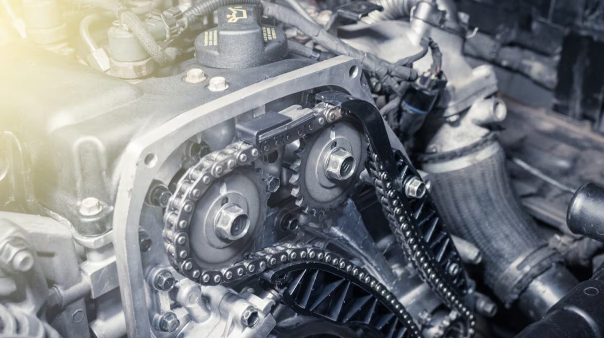 Meccanico controlla la cinghia di distribuzione su un motore, con strumenti e manuali, in un officina