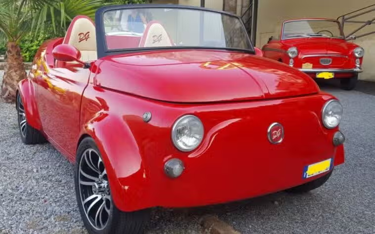 Una Fiat 500 modificata in una roadster con parabrezza basso e design ispirato alle Porsche, in un garage con luci soffuse