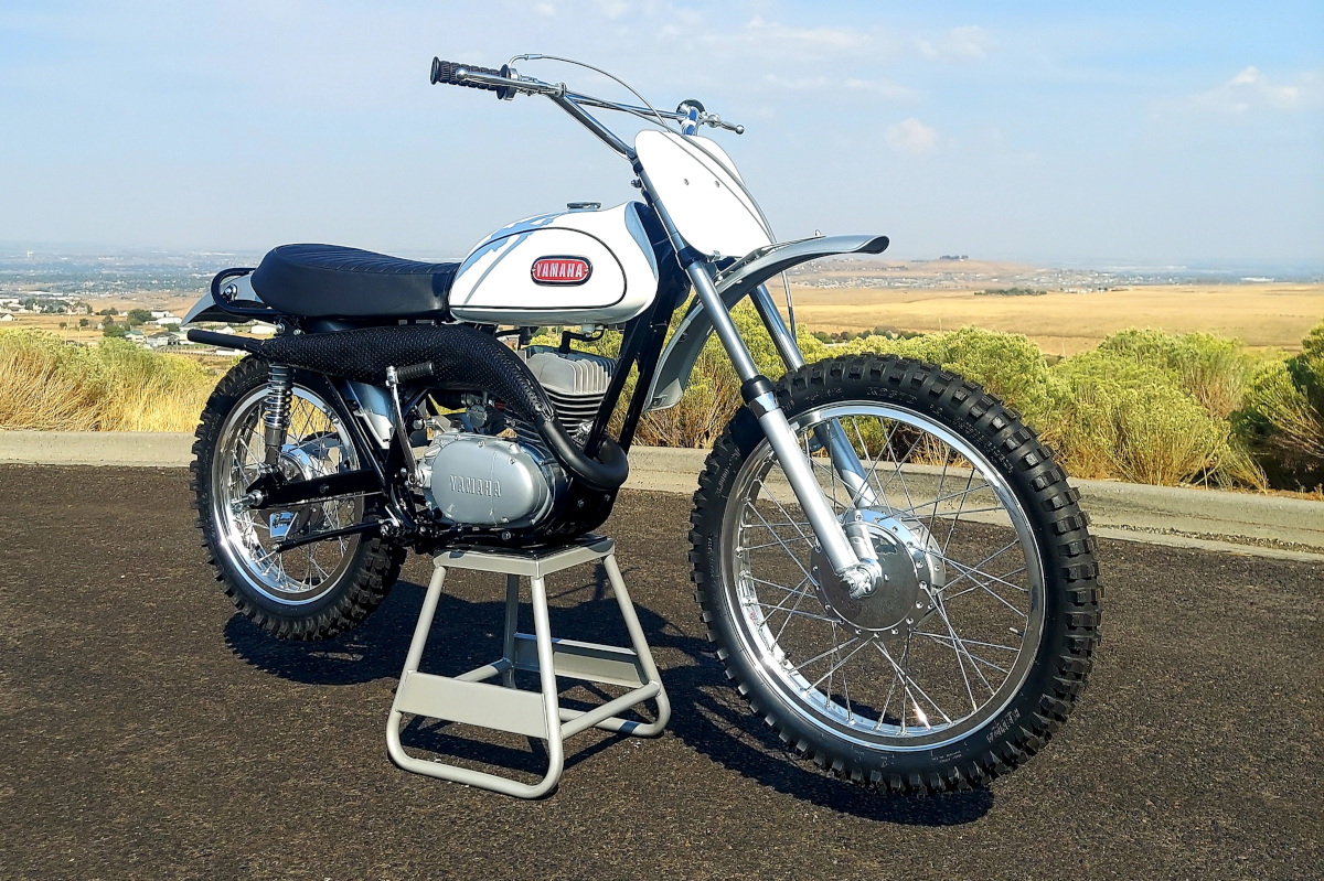 Un motociclista mostra la Yamaha DT1 1968 restaurata con il kit GYT, in un garage con attrezzi e pezzi d'epoca