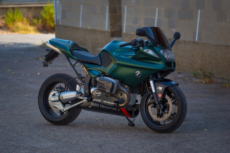 Una BMW R1100S con look sportivo e modifiche di alto livello, con telaio in alluminio e fibra di carbonio, in un garage con motocicli