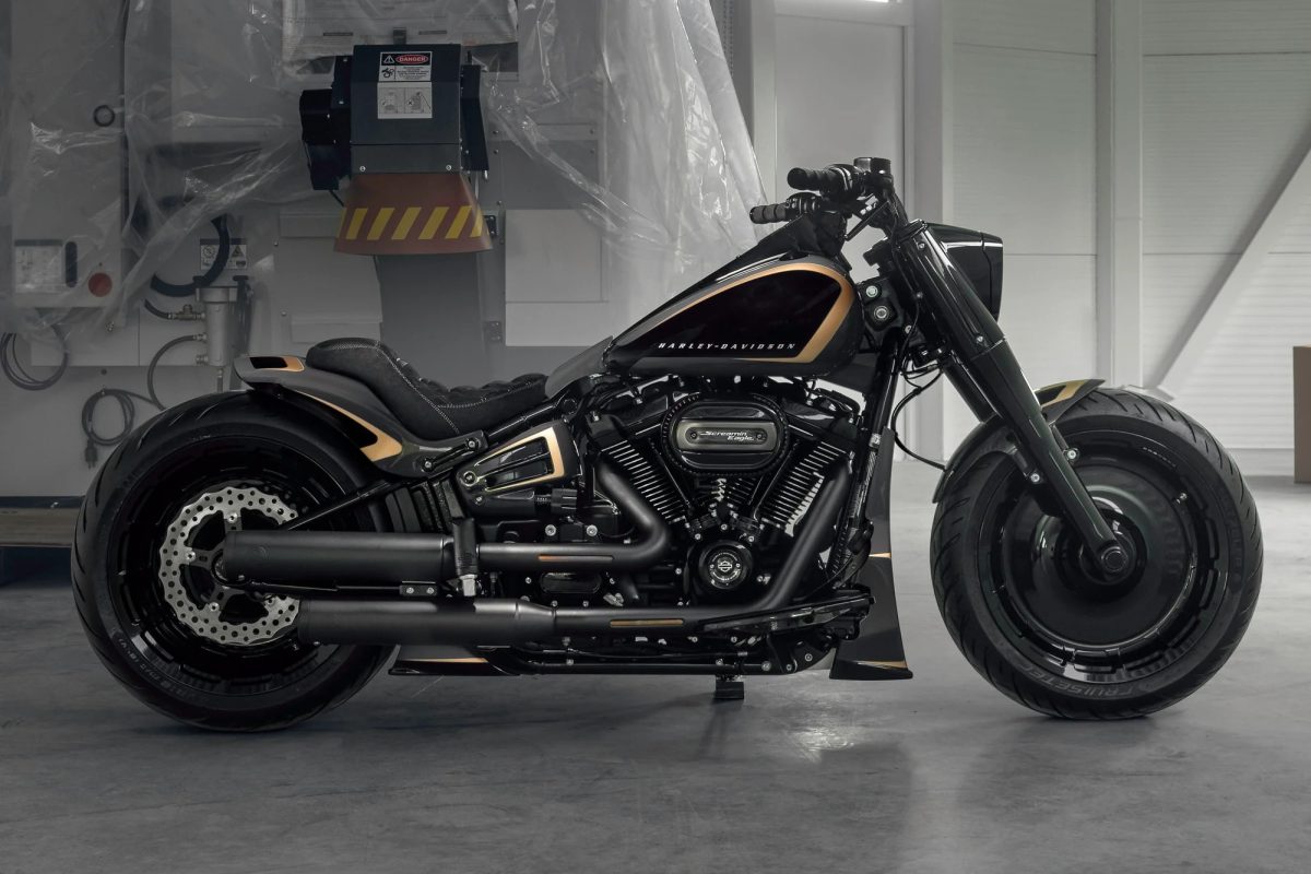 Una moto di colore nero con dettagli dorati e parafanghi personalizzati, con un look più aggressivo e minimalista